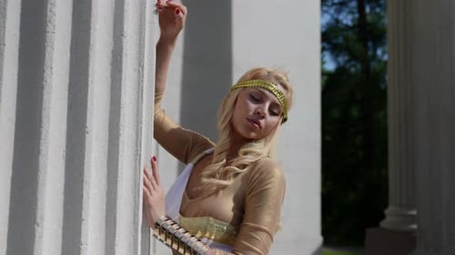 Portrait d'une blonde aux gros seins et dans un chiton grec à la colonne