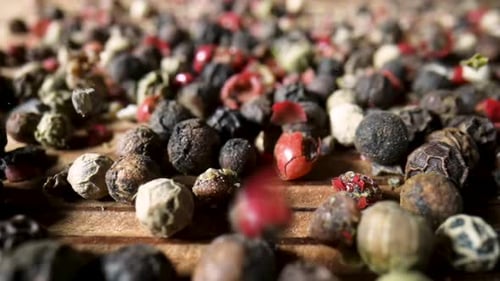 Vibrant Mixed Peppercorns Pouring onto Wooden Surface
