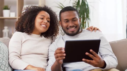 Couple Relaxing Together Using Tablet Inside Their Home