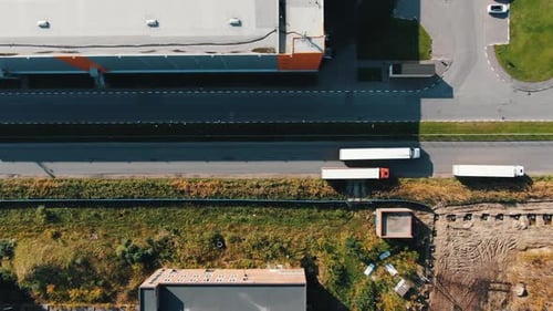 Truck Drives Along Empty Road Past Huge Storehouse Building