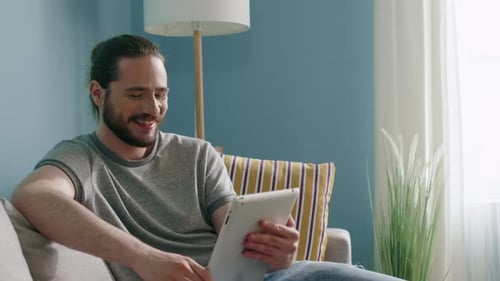 Young Man Relaxing with Tablet on Sofa