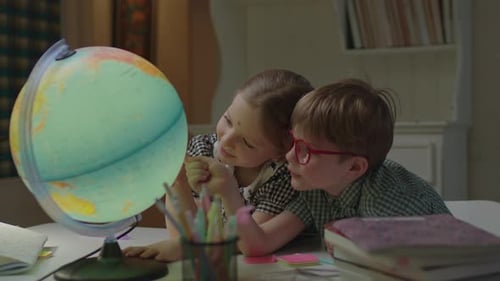 Girl and Boy Looking at Illuminated Globe
