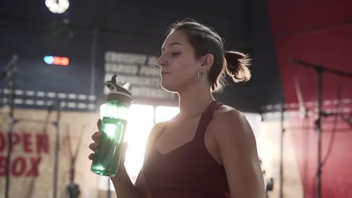 Young Woman Drinks Water in Fitness Center
