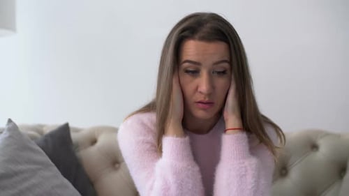 Woman Massaging Temples on Couch in Living Room