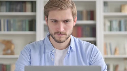 Smiling Young Adult Using Laptop in Home Setting