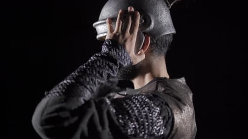 Man Putting on Silver Roman Soldier Helmet