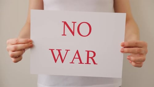 Close Up of a Protester Hands Holding Cardboard Banner with the Words No War
