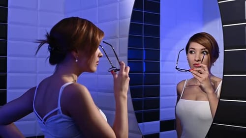 Stylish Young Woman Tries on Beautiful Glasses in Front of the Mirror