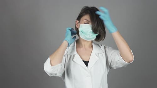 Female Surgeon in Green Gloves Getting Ready for Operation Putting Mask on