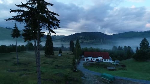 Aerial View of Rustic Building in Foggy Mountains