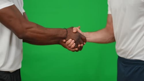 Unrecognizable Caucasian and African American Sportsmen Shaking Hands Leaving Green Screen