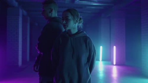 Dynamic Duo Dancing in Neon-Lit Urban Space