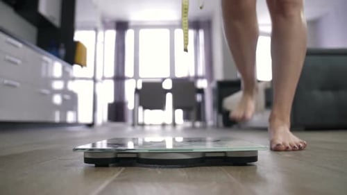 Woman Weighs Herself on Bathroom Scale at Home