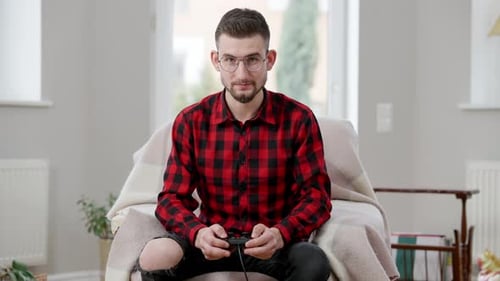 Konzentrierter kaukasischer junger Mann mit Gamecontroller beim Videospiel zu Hause