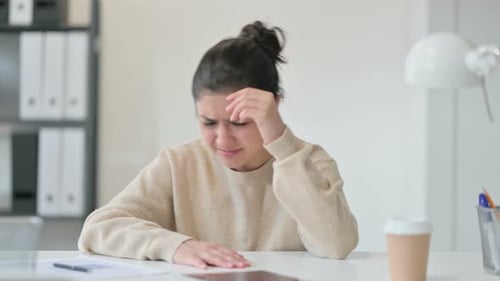 Woman With Headache Rubbing Temples at Desk