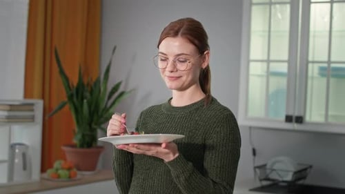 Woman Eating Salad with Gratification in Kitchen