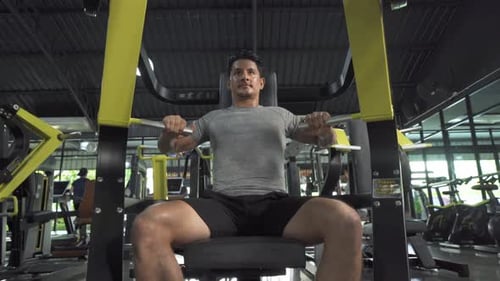 Man Lifting Weights at Gym on Seated Machine