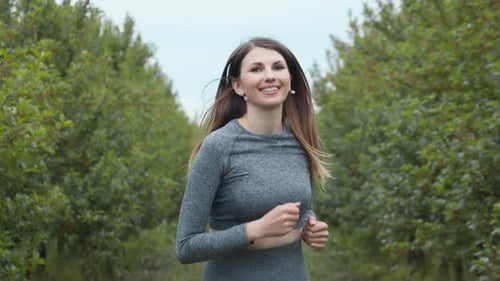 Woman Jogging in Green Tree-Lined Park