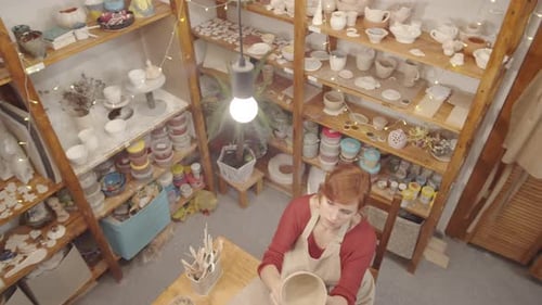 Caucasian Craftswoman Smoothing Surface of Wet Clay Bowl in Pottery Studio