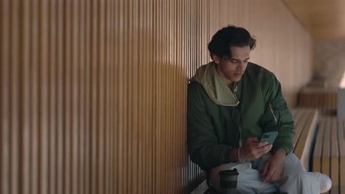 Young Man Using Phone Sitting on Bench