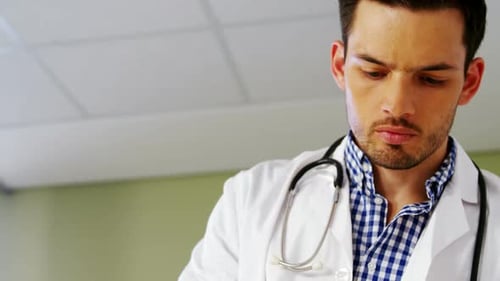 Male Doctor Reading Patient Information in Hospital