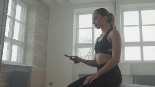 Sportive Girl Using Smartphone After Training At Gym