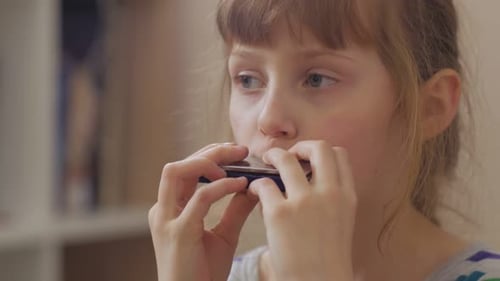 Child Plays Harmonica Close Up in Home Setting