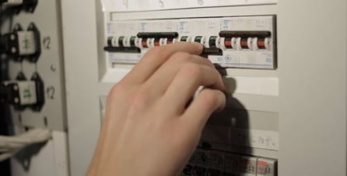Hand Turns on Circuit Breakers on Electrical Panel