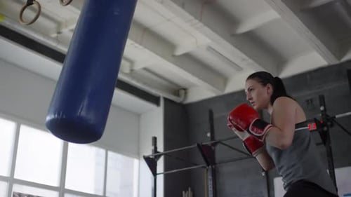 Woman Training with Punching Bag at the Gym