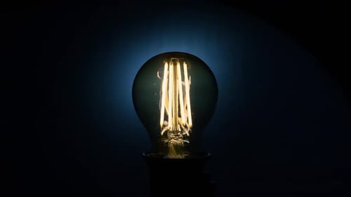 Elektrische Vintage Edison-Glühbirne mit spiralförmiger Blinkfunktion auf blauem Hintergrund