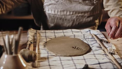 Young Woman Potter Makes a Design on the Clay Plate Using a Stamp in a Leaves Shape