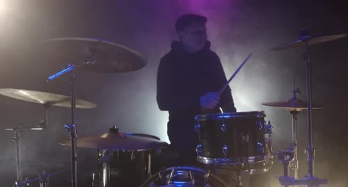 Drummer Energetically Plays Drum Kit in Smoky Studio