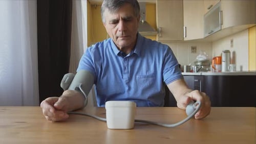 Man Using Blood Pressure Monitor At Home