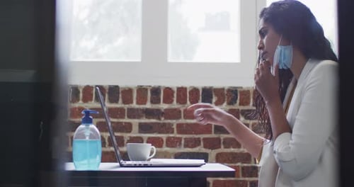 Woman drinking coffee while sitting on her desk at office