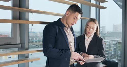 Man and a Woman Discussing Work in the Brightly Lit Modern Office. Concerned Male and Female Working