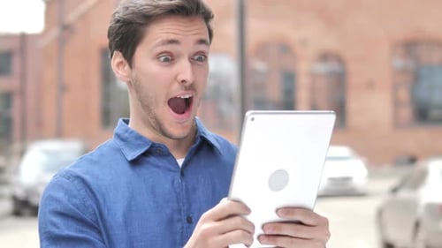 Man Reads Tablet and Reacts with Joy