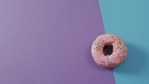 Video of donut with icing on purple and blue background