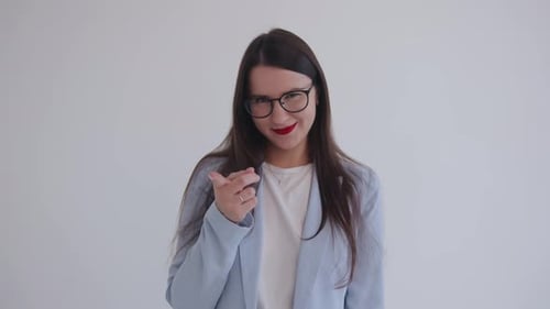 A Beautiful Young Business Lady in Glasses Threatens with Index Finger Narrowing Her Eyes and