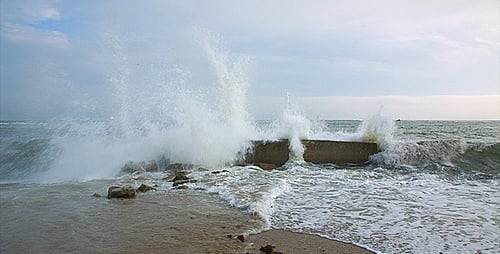 Waves Crashing Against Concrete Blocks on Beach