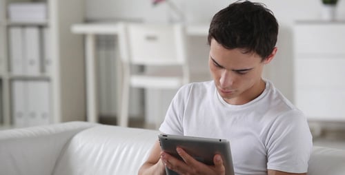 Young Man Using Tablet on Couch Indoors