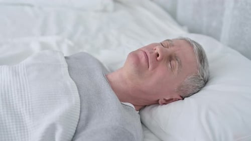 Vieil homme âgé dormant dans son lit et faisant un cauchemar