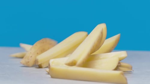 Potato Wedges Falling on Gray Surface, Blue Background