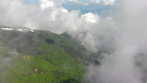 Montagne Boisée Aérienne Avec Des Fragments De Neige Parmi Les Nuages Au Printemps