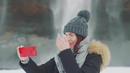 Young Beautiful Woman Takes a Selfie on the Background of a Waterfall Selanjafoss Iceland