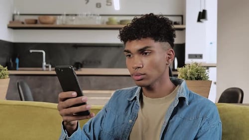 Young Adult Relaxing at Home Using Smartphone