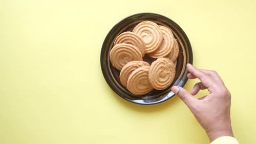 Hand Selecting Swirl Cookie from Plate, Top Down