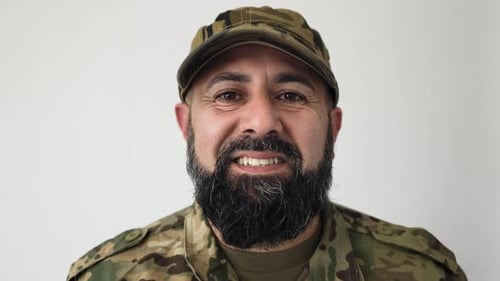 Smiling man with beard wearing military fatigues