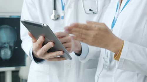Closeup of Male and Female Hands Doctors Using Tablet and Gesturing During Professional Conversation