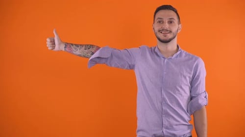 Smiling Man Gives Thumbs Up on Orange Background