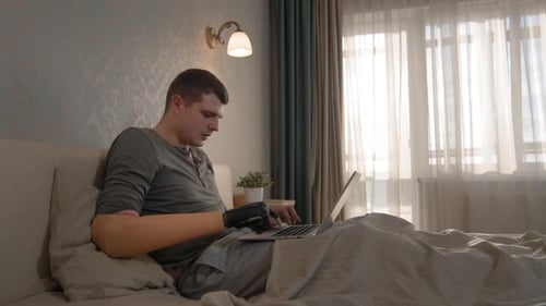 Kaukasischer Amputiierter arbeitet zu Hause am Laptop